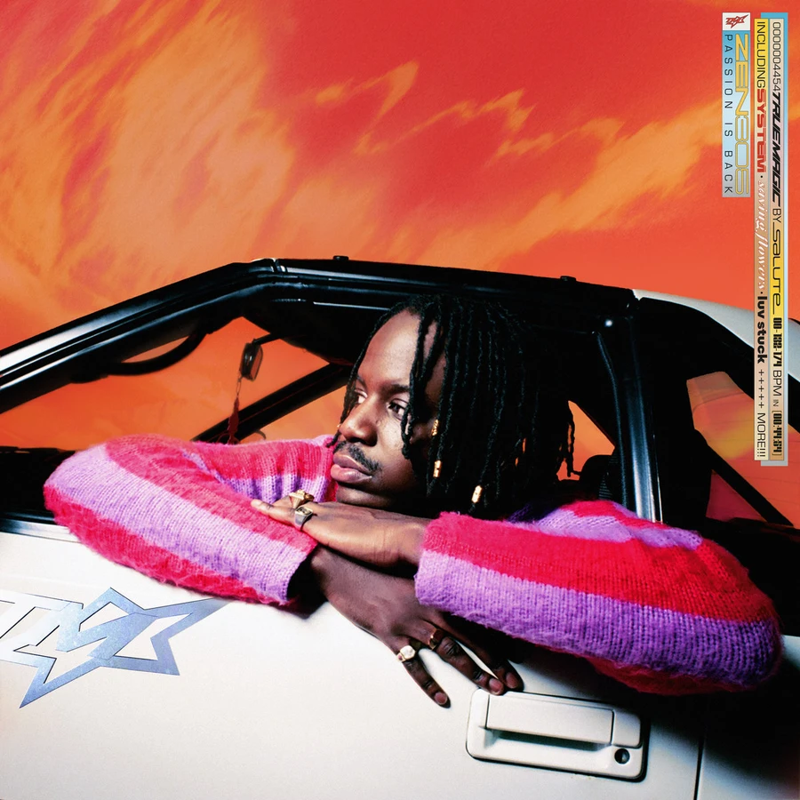 A Black man wearing a colorful sweater leans out the window of a car.